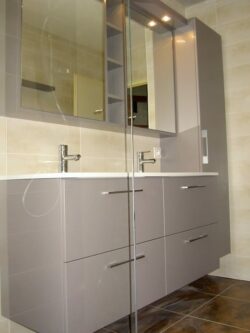 Meuble double vasque gris et blanc avec rangement en hauteur également.