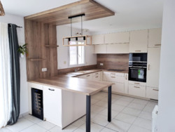 Cuisine beige et bois en U, avec table intégrée.