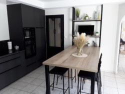 Cuisine familiale et très contemporaine par la couleur noire qui domine. Le plan de table, en coloris bois réchauffe l'ensemble. Création d'une cuisine sur-mesure contemporaine, noire et bois en Vendée.