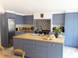 Cuisine style campagnard dans un joli bleu pastel. Grand îlot central pour un bel espace de plan de travail. Cuisine sur-mesure bleue et bois en Vendée