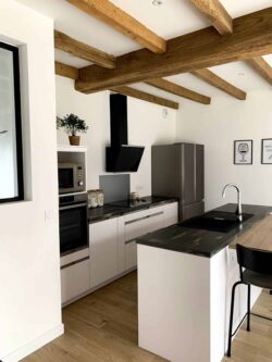 Cuisine ouverte familiale dans les tons blanc et bois.