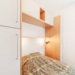 Tête de lit dans une petite chambre intégrant des rangements en hauteur et une colonne de chaque côté du lit.
Projet Architecture ML - Photo Atelier Kuryo. Tête de lit intégrant des rangements